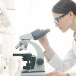 Laboratory professional using a microscope at a cleanroom workbench designed for precision, cleanliness, and efficient laboratory workflows.
