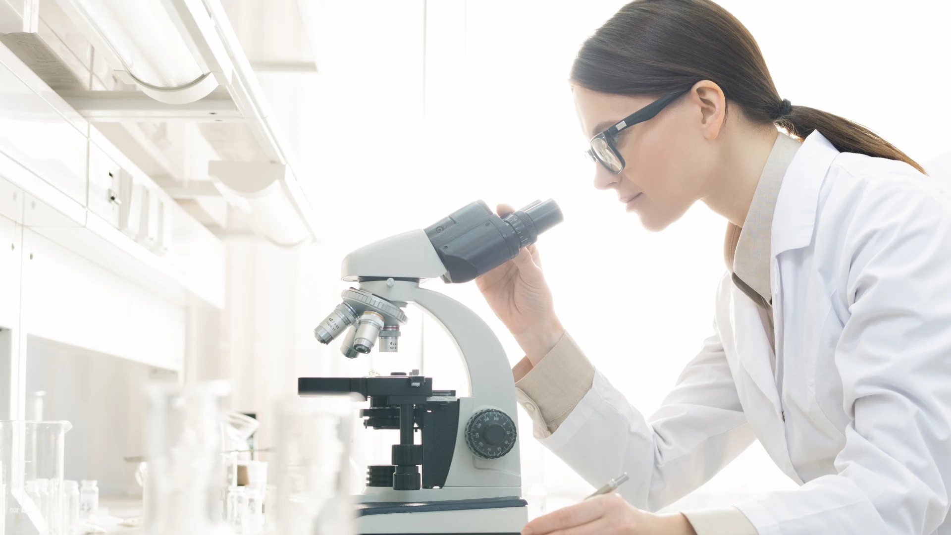 Laboratory professional using a microscope at a cleanroom workbench designed for precision, cleanliness, and efficient laboratory workflows.