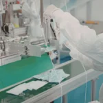 Cleanroom technician working with manufacturing equipment in a space-efficient cleanroom production area.